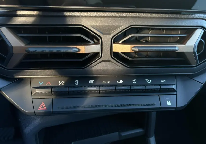 Détail du tableau de bord du Dacia Duster 2025, montrant les aérateurs hexagonaux et les commandes de climatisation.