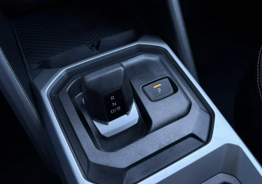 Gros plan sur le levier de vitesses et bouton de frein à main électrique du Dacia Duster gris Schiste, intérieur moderne.