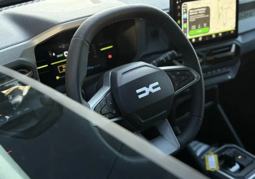 Vue rapprochée du volant et tableau de bord digital du Dacia Duster 2025, intérieur moderne avec écran tactile GPS.