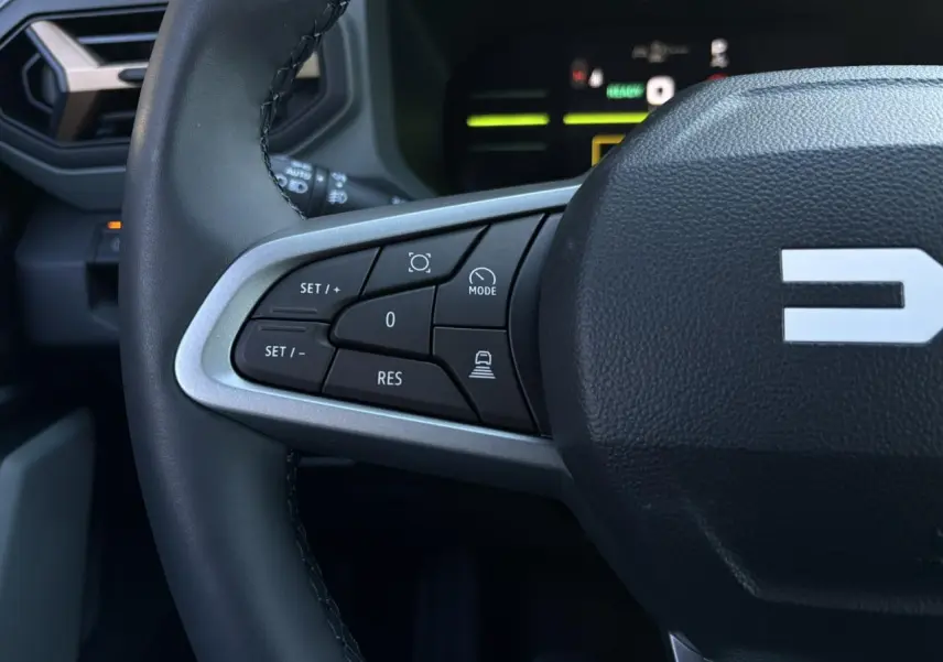 Gros plan sur la partie gauche du volant noir du Dacia Duster 2025, avec commandes de régulateur de vitesse.