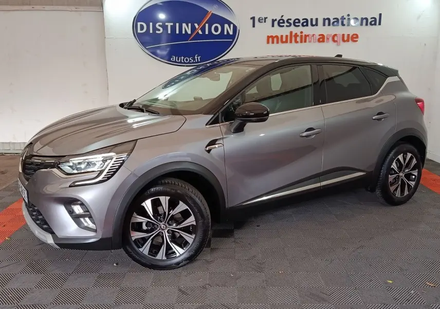 Renault Captur Techno TCe 90 gris foncé vu de profil côté gauche, avec jantes alliage et feux LED allumés.