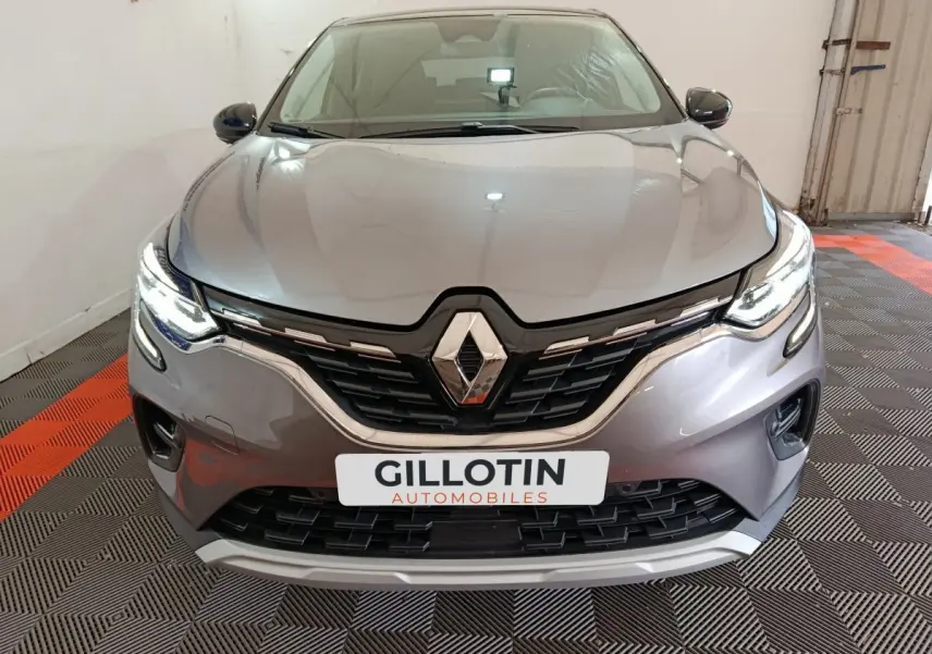 Vue frontale du Renault Captur techno TCe 90 gris foncé avec phares LED allumés et calandre distinctive.
