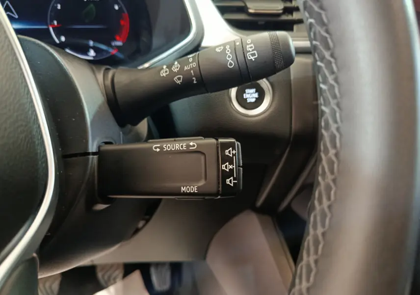 Gros plan sur la commande multifonction et bouton démarrage du tableau de bord du Renault Captur gris foncé 2024.