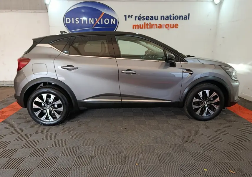 Profil côté gauche d'un Renault Captur Techno TCe 90 gris foncé 2024 avec jantes alliage et toit noir contrasté.