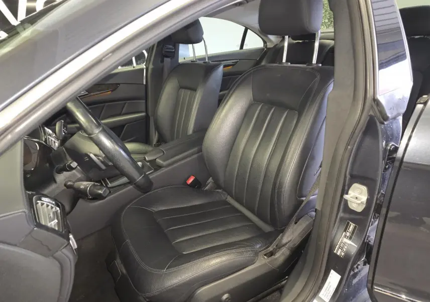 Vue intérieure côté conducteur d'une Mercedes Classe CLS 250 CDI gris avec sièges en cuir noir et volant multifonctions.