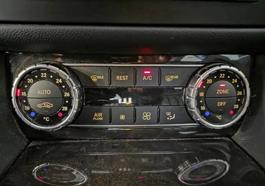 Gros plan sur la commande de climatisation automatique 3 zones de la Mercedes CLS 250 CDI gris, avec affichage digital et boutons rétroéclairés.