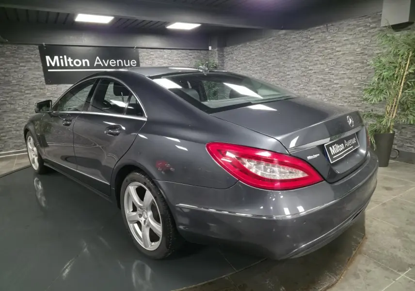 Mercedes Classe CLS gris métallisé vue 3/4 arrière droit avec jantes alliage 5 branches en intérieur showroom