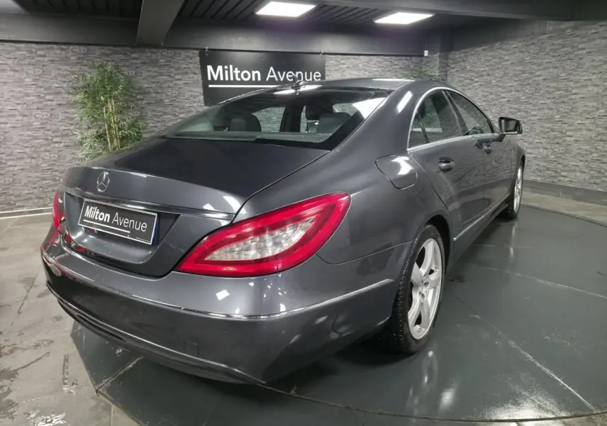 Mercedes Classe CLS gris métallisé vue 3/4 arrière droit avec jantes alliage 5 branches en intérieur showroom.