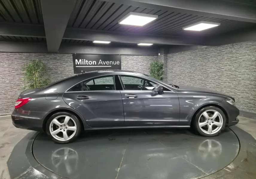 Profil droit d'une Mercedes Classe CLS 250 CDI gris métallisé avec jantes alliage 5 branches en showroom.