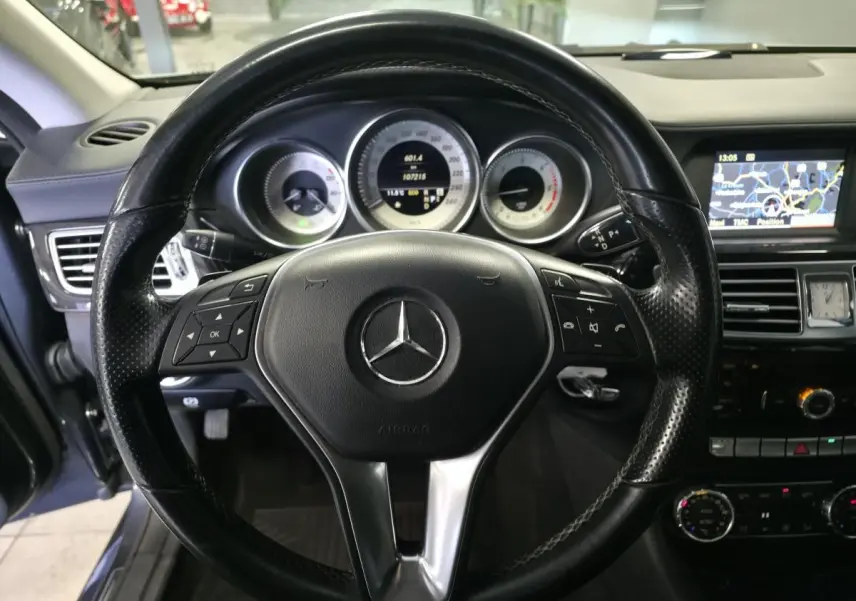 Vue intérieure centrée sur le volant cuir noir de la Mercedes Classe CLS 250 CDI avec tableau de bord et écran de navigation.