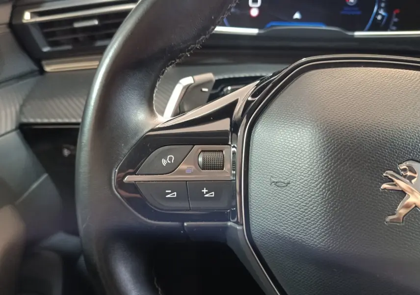 Gros plan sur le volant cuir noir du Peugeot 508 2020 avec commandes multifonctions et tableau de bord numérique.