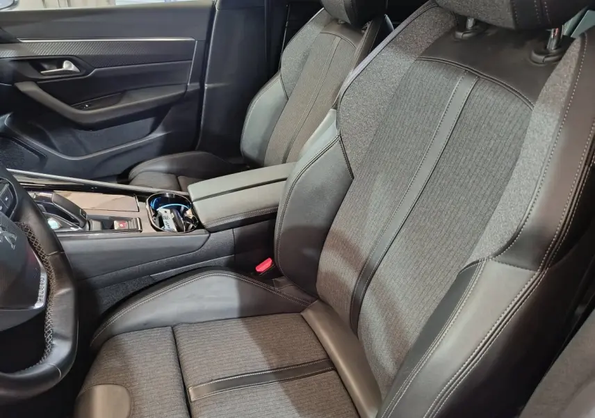 Vue intérieure côté conducteur de la Peugeot 508 gris clair, sièges tissu et cuir avec console centrale moderne.