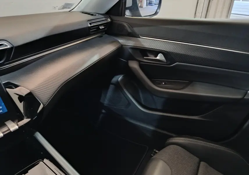 Vue intérieure côté passager de la Peugeot 508 2020 gris clair, tableau de bord texturé et garnitures noires.
