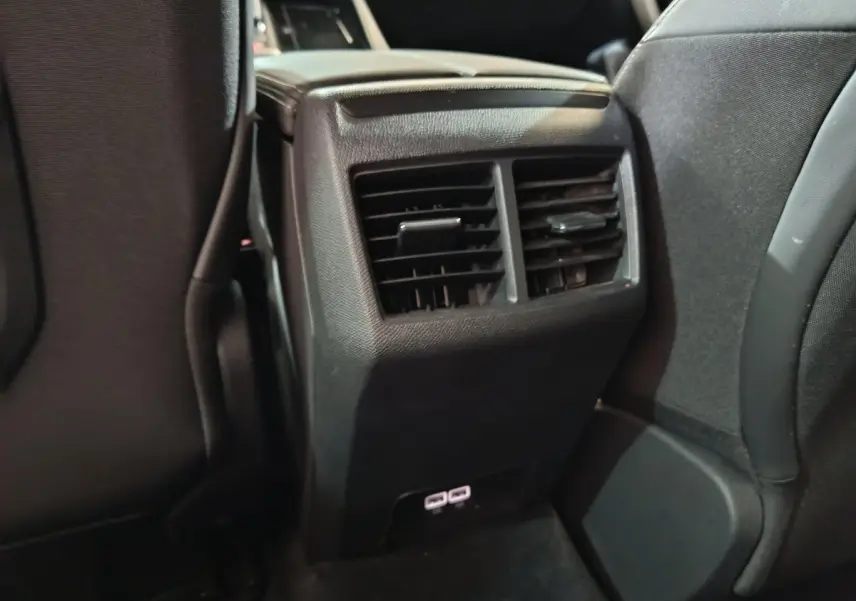 Détail des aérateurs arrière noirs et ports USB sous la console centrale entre les sièges avant d’une Peugeot 508 gris clair.