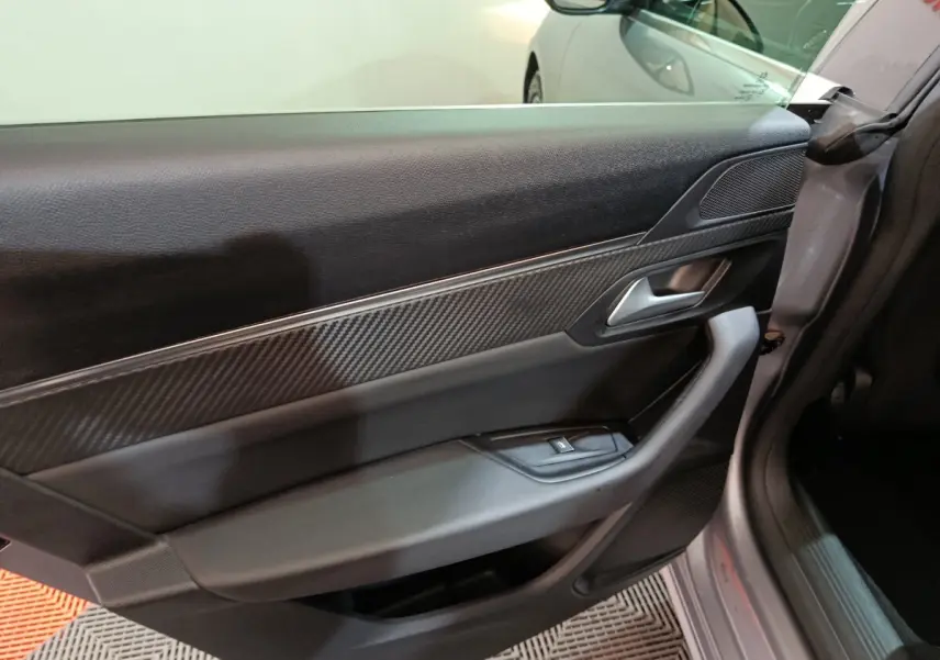 Vue intérieure côté gauche de la porte avant gris clair de la Peugeot 508 avec insert effet carbone et poignée argentée.