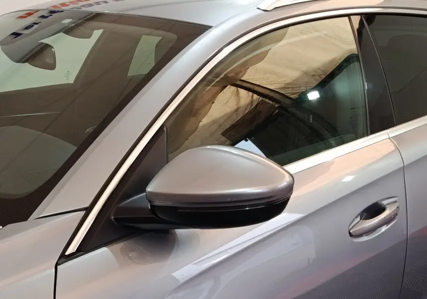 Vue rapprochée côté gauche d'une Peugeot 508 gris clair, mettant en valeur le rétroviseur et la poignée de porte.