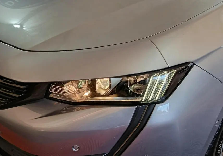 Gros plan sur le phare avant droit d'une Peugeot 508 gris clair, mettant en valeur les feux LED distinctifs.