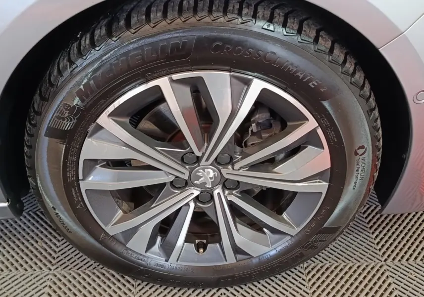 Gros plan sur la roue avant droite gris clair d'une Peugeot 508 avec jante alliage et logo Peugeot central.