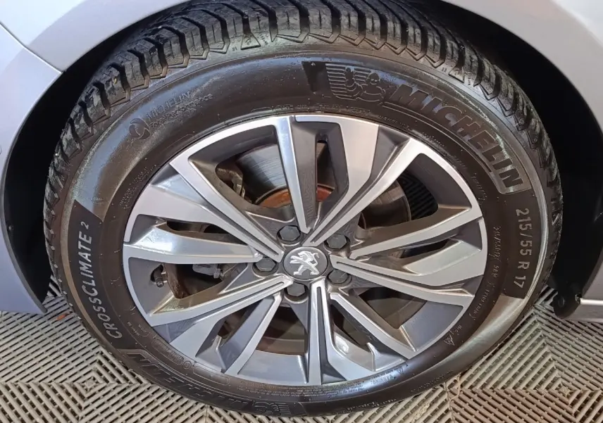 Gros plan sur la roue avant droite gris clair d'une Peugeot 508 avec jante alliage et pneu Michelin CrossClimate 2.