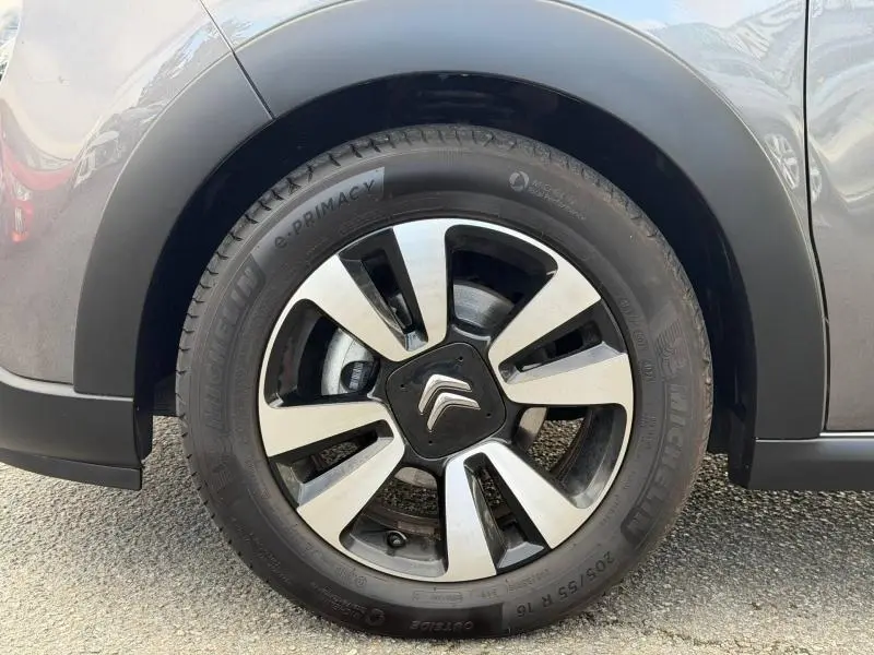 Gros plan sur la roue avant droite d'une Citroën C3 2023 gris Platinium avec jante alliage bicolore et logo Citroën central.