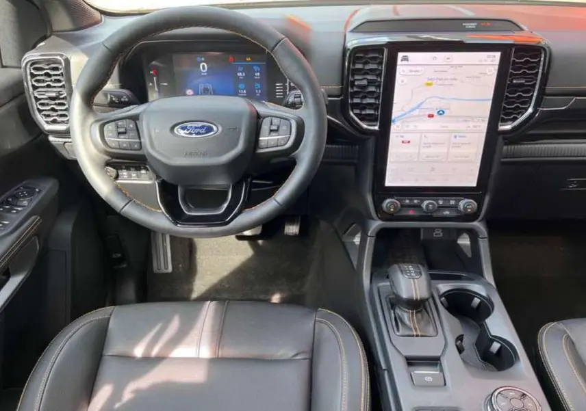 Vue intérieure frontale du Ford Ranger Wildtrak noir agate, volant cuir multifonctions et écran tactile vertical 12 pouces.