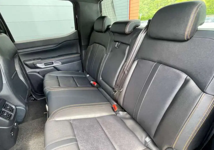 Vue latérale intérieure sur la banquette arrière en cuir noir avec surpiqûres contrastantes du Ford Ranger Wildtrak 2025.