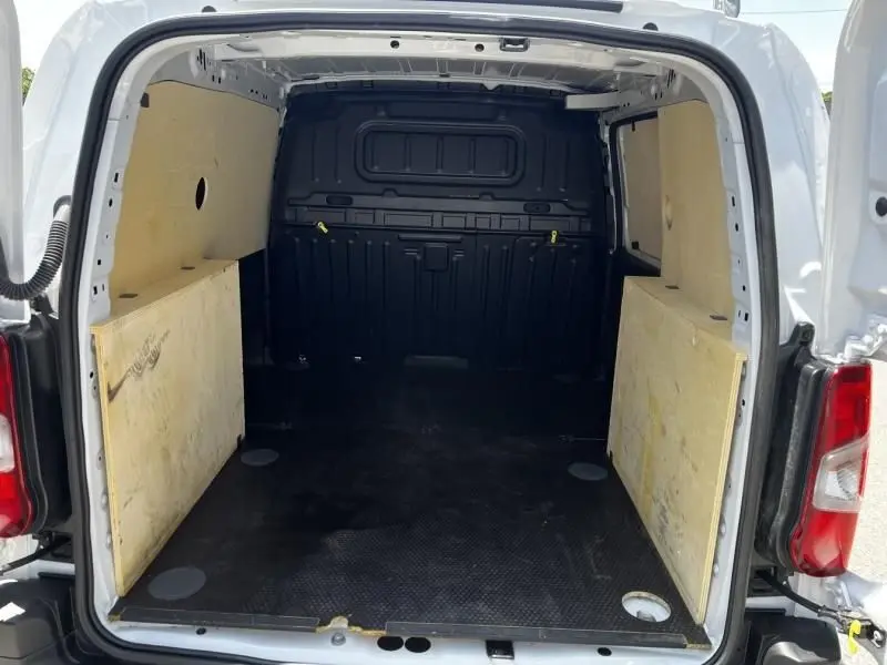 Vue arrière de l’intérieur blanc d’un Opel Combo Cargo 2024 avec aménagements en bois sur les côtés du coffre.