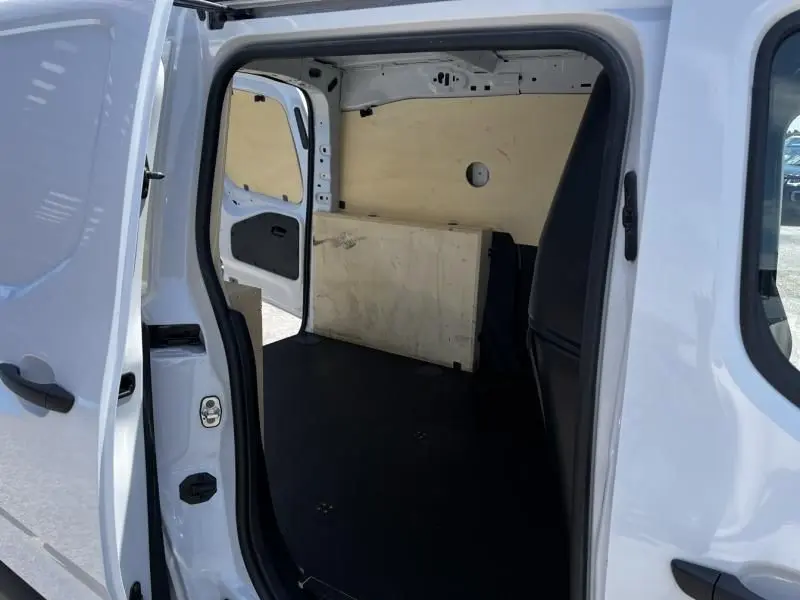 Vue intérieure par la porte latérale ouverte d’un Opel Combo Cargo blanc 2024, montrant l’espace de chargement vide.