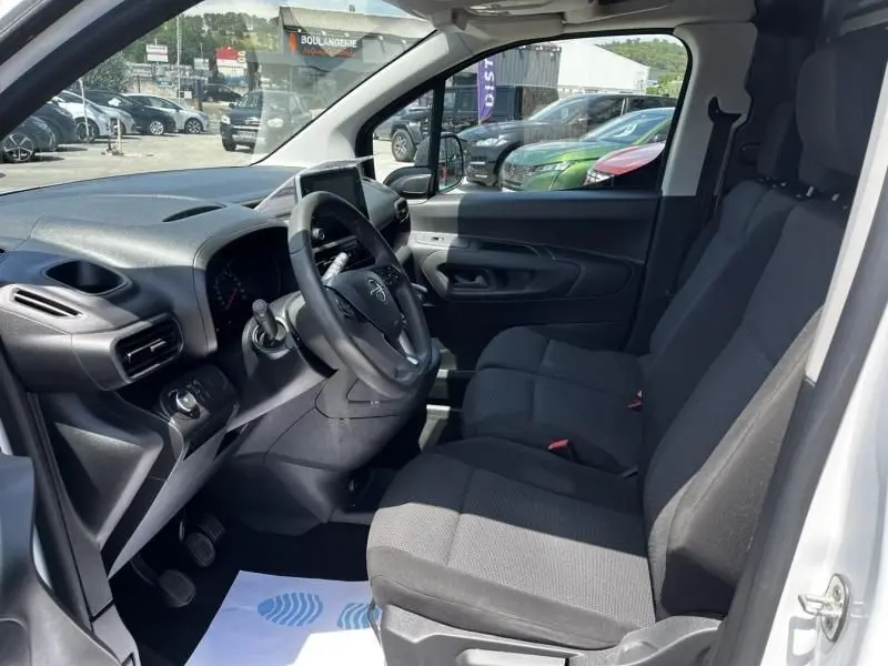 Intérieur côté conducteur de l’Opel Combo Cargo blanc 2024, montrant le tableau de bord et les sièges avant en tissu noir.