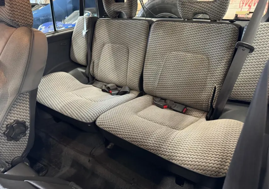 Vue intérieure arrière du Mitsubishi Pajero Court 2.8 TD 1997, sièges en tissu gris à motifs tressés.