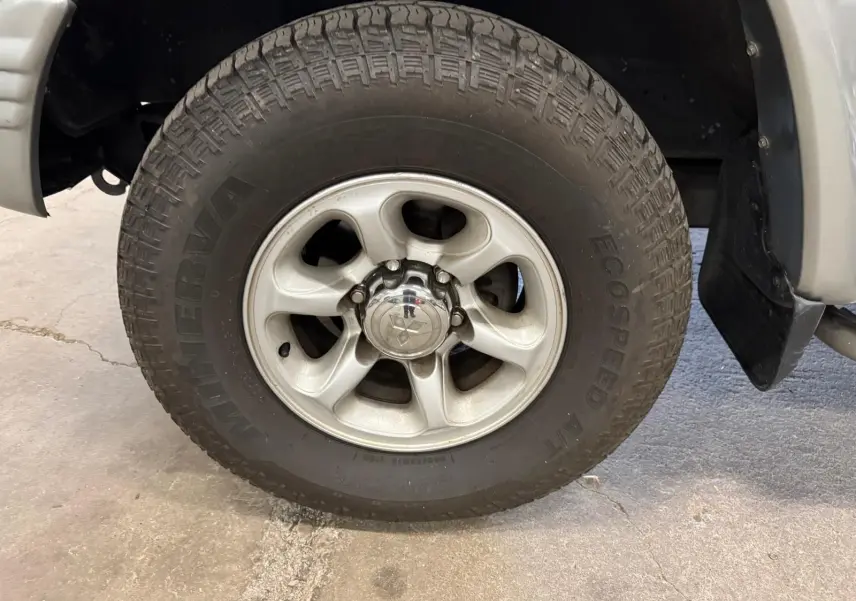 Gros plan sur la roue avant droite gris aluminium du Mitsubishi Pajero Court 2.8 TD avec jante alliage et marche-pied visible.