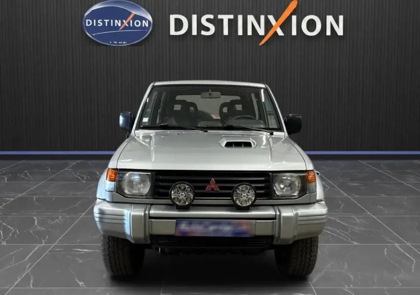 Vue de face du Mitsubishi Pajero Court gris aluminium de 1997 avec phares additionnels et prise d'air sur le capot.