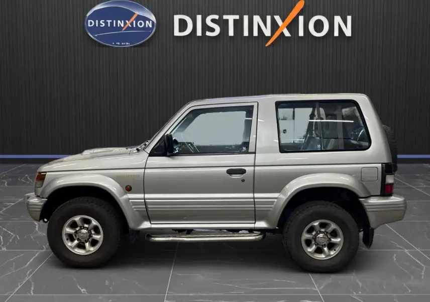 Profil droit du Mitsubishi Pajero Court gris aluminium de 1997 avec marchepieds et jantes alliage 15 pouces.