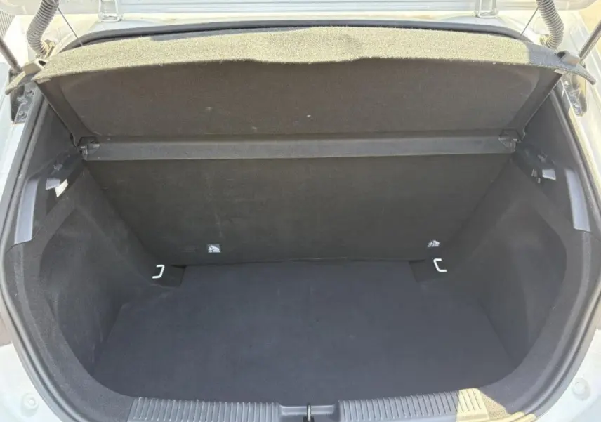 Coffre ouvert vu de l'arrière d'une MG3 1.5 HYBRID+ 195 COMFORT blanche, montrant un espace de rangement vide et propre.