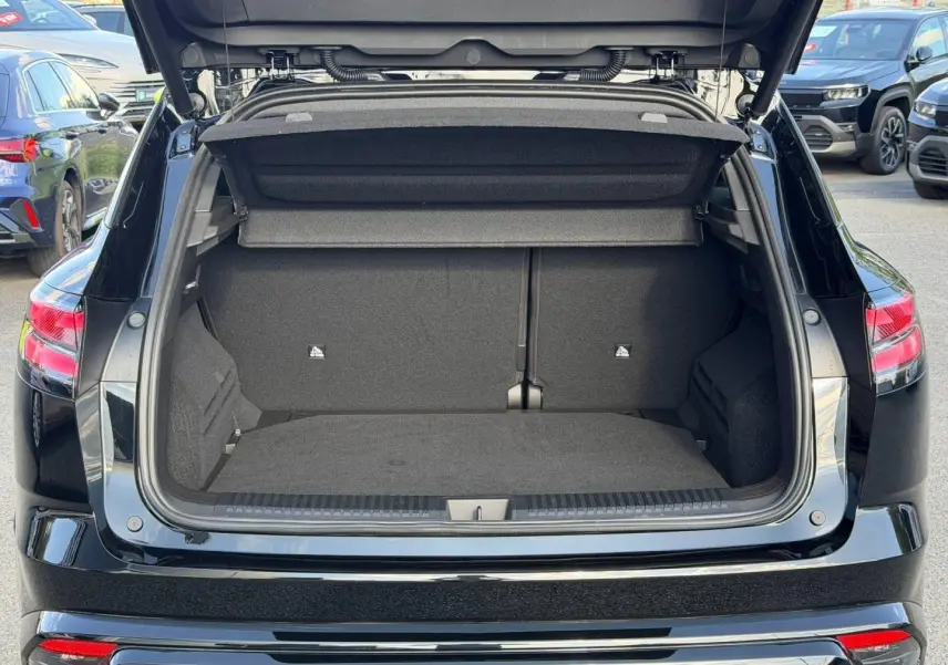 Coffre ouvert vu de l'arrière d'un Renault Austral noir étoilé métallisé, avec banquette arrière rabattable visible.