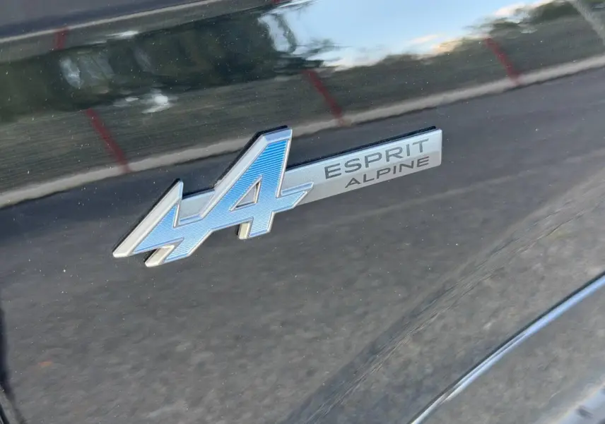 Gros plan sur l’inscription Esprit Alpine bleue sur la carrosserie noir étoilé métallisé du Renault Austral.