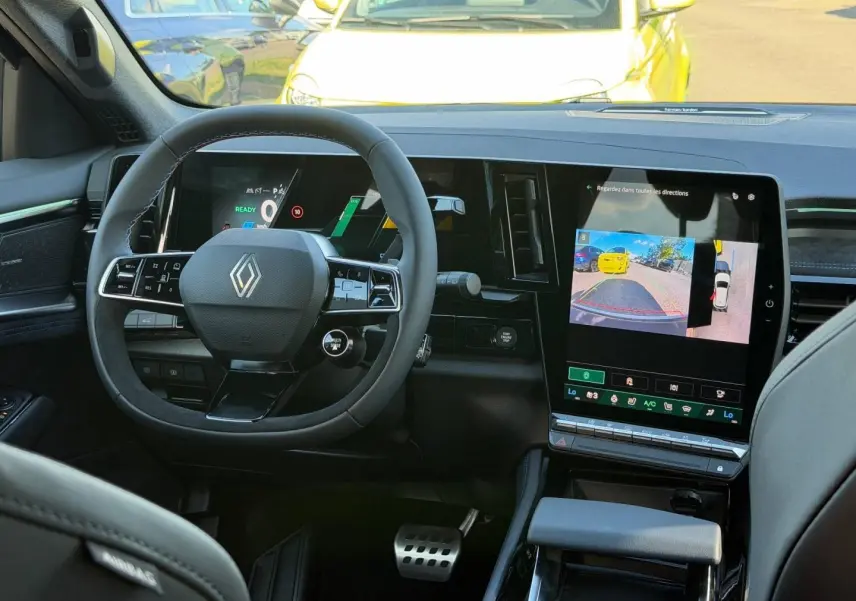 Vue intérieure frontale du tableau de bord noir du Renault Austral 2026 avec écran tactile et volant multifonction.