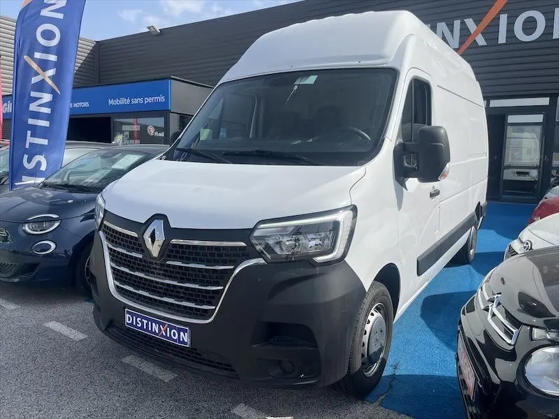 Vue 3/4 avant droite d’un Renault Master blanc stationné devant un concessionnaire avec calandre noire et logo Renault visible.