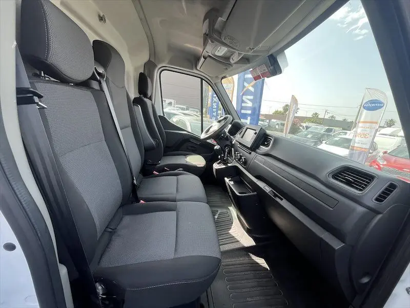Vue intérieure côté conducteur du Renault Master blanc 2021, montrant les sièges avant et le tableau de bord moderne.