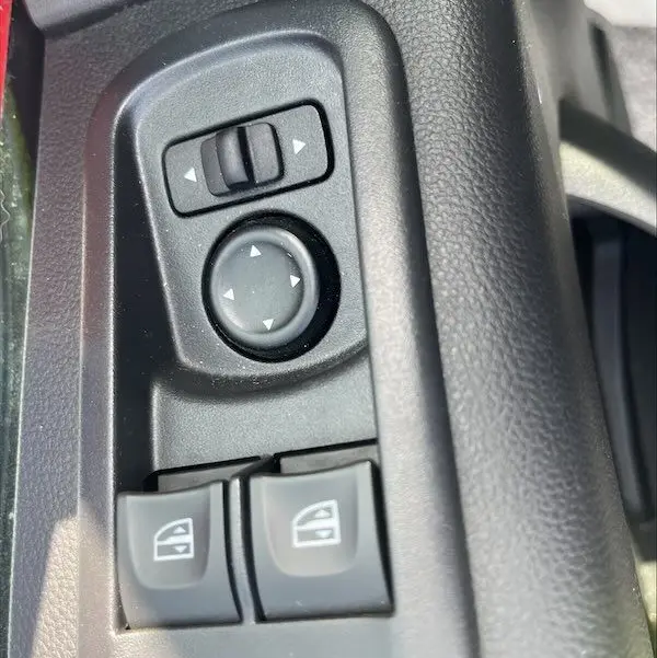 Gros plan sur les commandes de réglage des rétroviseurs et des vitres électriques côté conducteur du Renault Master blanc 2021.