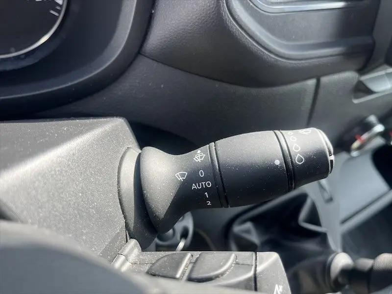 Gros plan sur la manette d'essuie-glace noire du Renault Master blanc, côté conducteur, avec commandes visibles.