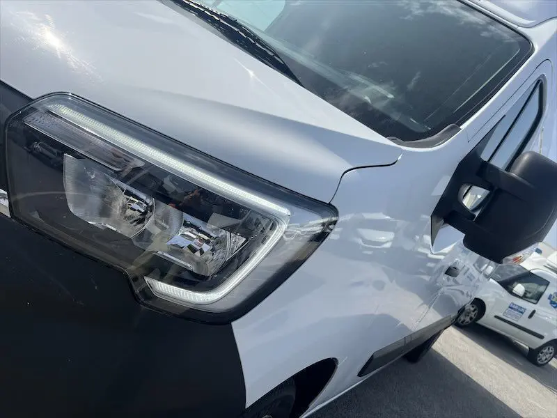 Vue rapprochée du phare avant gauche du Renault Master blanc 2021, soulignant son design moderne et le rétroviseur noir.
