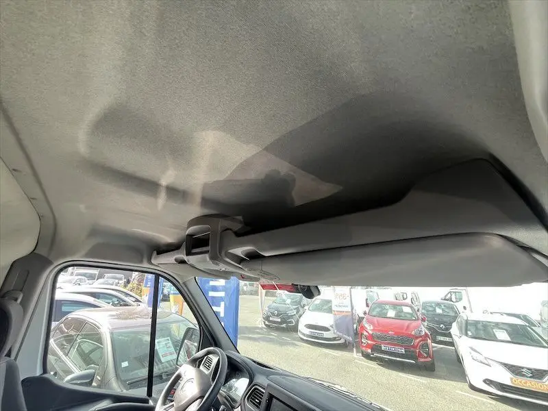 Intérieur du Renault Master blanc 2021, vue du plafond et pare-soleil côté conducteur avec parking en arrière-plan.