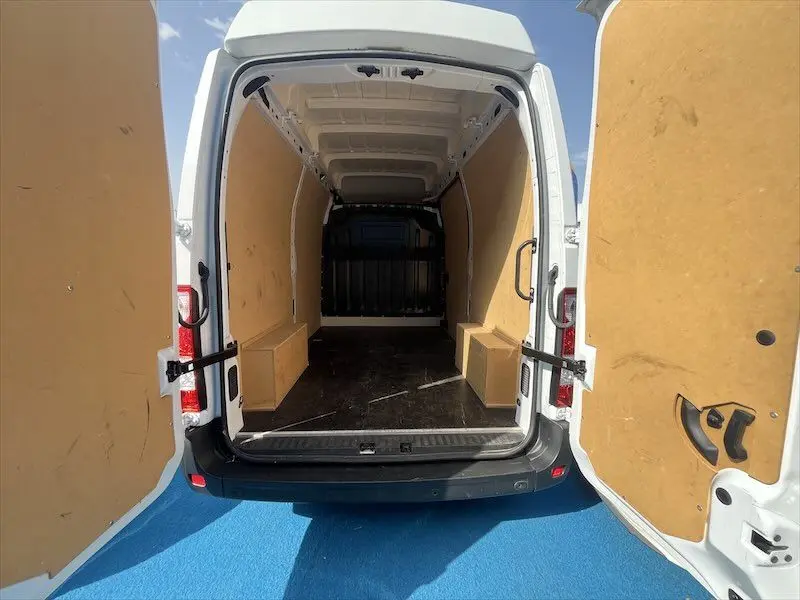 Vue arrière ouverte du Renault Master blanc 2021, montrant l'intérieur spacieux avec revêtement bois clair et sol noir.