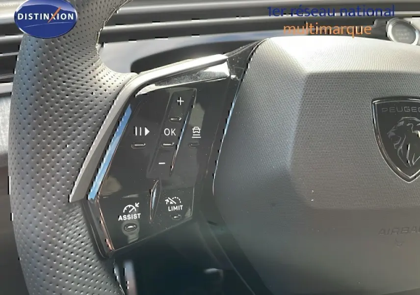 Gros plan sur le volant noir perforé du Peugeot 3008 2025 avec commandes intégrées et logo lion au centre.
