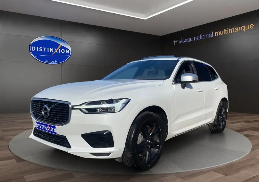 Volvo XC60 D4 R-Design blanc en 3/4 avant droit avec jantes noires et calandre distinctive noire.