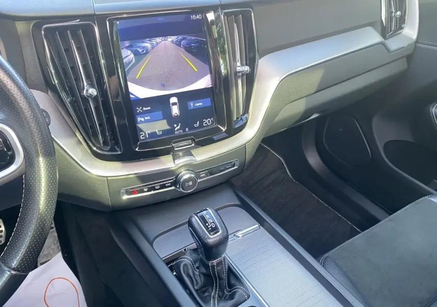 Vue intérieure centrée sur la console centrale et écran tactile affichant la caméra de recul du Volvo XC60 blanc.