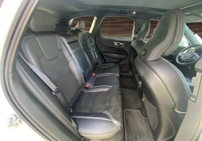Intérieur arrière du Volvo XC60 blanc 2019, sièges cuir noir avec surpiqûres blanches, vue côté gauche depuis la porte ouverte.