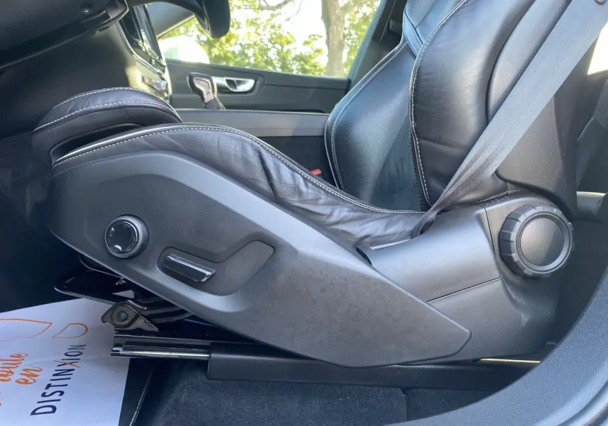 Gros plan sur le siège conducteur en cuir noir avec réglages électriques du Volvo XC60 D4 blanc, intérieur côté gauche.