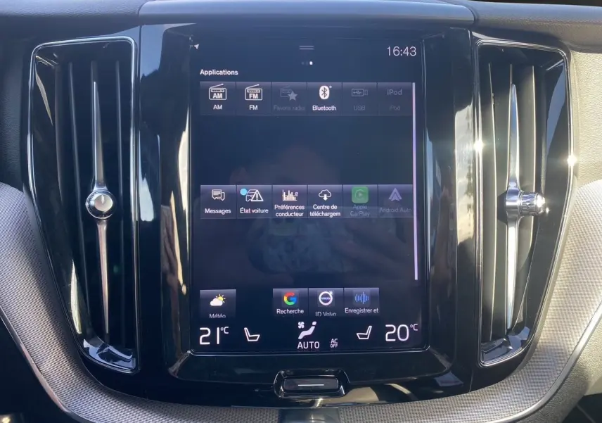 Écran tactile central du tableau de bord du Volvo XC60 blanc 2019, avec commandes climatisation et ventilation visibles.